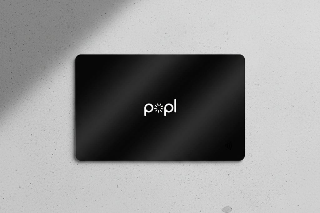 A black Popl NFC card resting on a concrete surface
